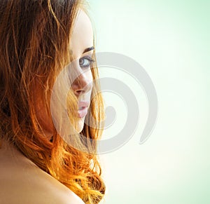 Beautiful girl with long red hair with green eyes looking out over the shoulder on a white background