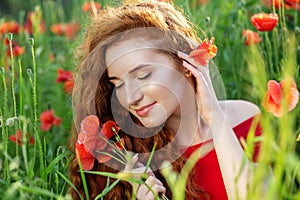 Beautiful girl with long red hair. Poppy field. The concept of health, nature, cosmetics and care