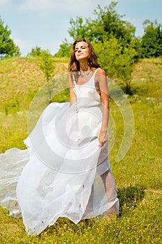 Beautiful girl in long white dress standing on