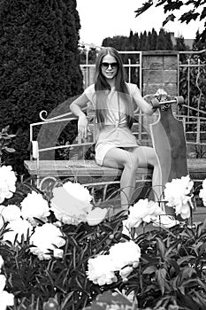 Beautiful girl with longboard sits on bench in