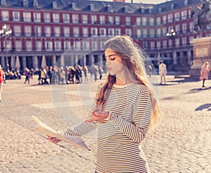 Beautiful girl looking at a map in Plaza Mayor Madrid feeling lost and looking for directions