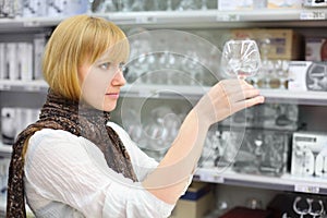 Beautiful girl looks at glass in shop