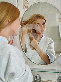 The beautiful girl looks in a mirror in a bathroom