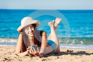 Beautiful girl lying on a beach and talking the phone