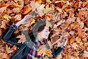 Beautiful girl lying on fallen leaves of maple tree autumn