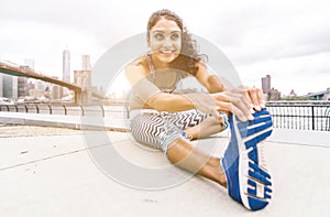 Beautiful girl making stretching before intense running in New york city