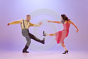 Beautiful girl and man in colorful retro style costumes dancing incendiary dances  on lilac color background in