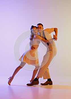 Beautiful girl and man in retro style costumes dancing incendiary dances  on gradient lilac color background in