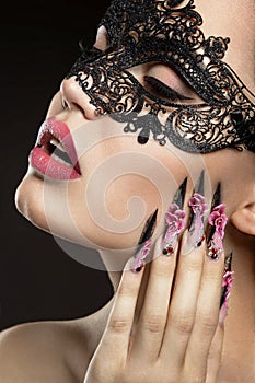 Beautiful girl in a mask with long fingernails. photo