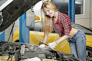 Beautiful girl mechanic repairing a car