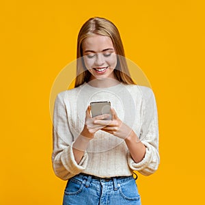 Beautiful Girl Messaging On Smartphone Over Orange Background