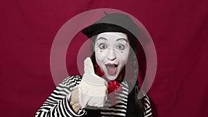 Beautiful girl mime smiles, shows thumb up and nods approvingly while looking at the camera. Beautiful girl in the image