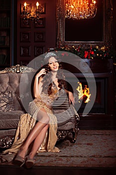 Beautiful girl model celebrates Christmas or New Year in a classic interior, near a New Year tree, spruce. Holiday woman with