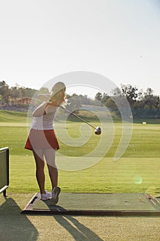 Beautiful girl at the moment of impact while playing golf