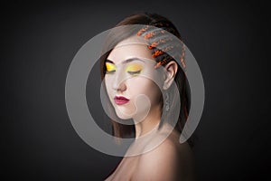 Beautiful girl on a monochrome studio background with bright makeup. Woman with pigtails from the side