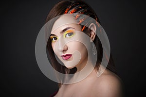 Beautiful girl on a monochrome studio background with bright makeup. Woman with pigtails from the side