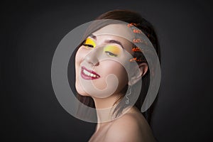 Beautiful girl on a monochrome studio background with bright makeup. Woman with pigtails from the side