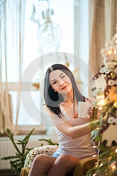 Beautiful girl in the morning with a cup in the New Year`s interior. Woman at home at Christmas time in a bedroom in a rustic styl