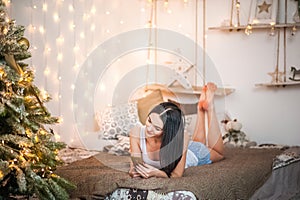 Beautiful girl in the morning with a cup in the New Year`s interior. Woman at home at Christmas time in a bedroom in a rustic styl