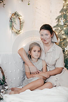 Beautiful girl and mother near Christmas tree. Rustic style