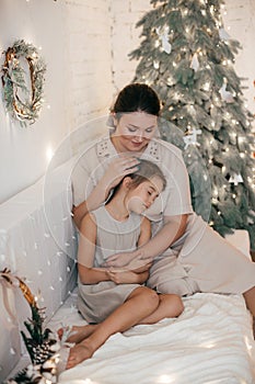 Beautiful girl and mother near Christmas tree. Rustic style