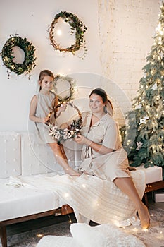 Beautiful girl and mother near Christmas tree. Rustic style