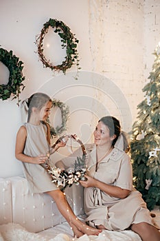 Beautiful girl and mother near Christmas tree. Rustic style