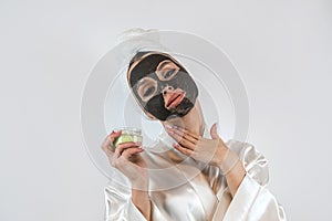 Beautiful girl with mud oy black clay facial mask isolated on white