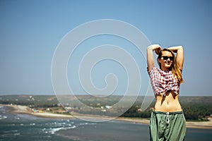 Beautiful girl with naked belly relaxing on sea rocks