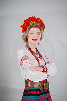 A beautiful girl in National Ukrainian Costume. captured in studio. Embroidery and jacket. wreath. circlet of flowers. red lips