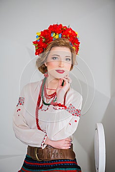 A beautiful girl in National Ukrainian Costume. captured in studio. Embroidery and jacket. wreath. circlet of flowers. red lips