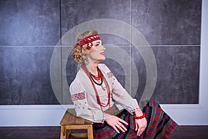 A beautiful girl in National Ukrainian Costume. captured in studio. Embroidery and jacket. wreath. circlet of flowers. red lips