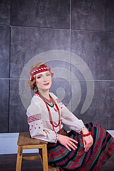A beautiful girl in National Ukrainian Costume. captured in studio. Embroidery and jacket. wreath. circlet of flowers. red lips