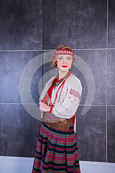 A beautiful girl in National Ukrainian Costume. captured in studio. Embroidery and jacket. wreath. circlet of flowers. red lips