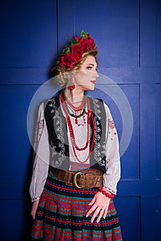 A beautiful girl in National Ukrainian Costume. captured in studio. Embroidery and jacket. wreath. circlet of flowers. red lips