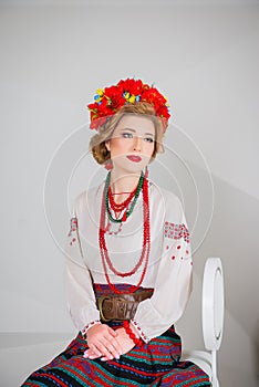 A beautiful girl in National Ukrainian Costume. captured in studio. Embroidery and jacket. wreath. circlet of flowers. red lips