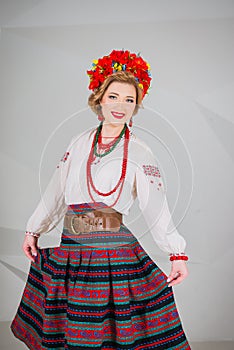 A beautiful girl in National Ukrainian Costume. captured in studio. Embroidery and jacket. wreath. circlet of flowers. red lips