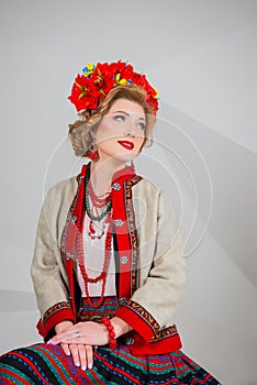 A beautiful girl in National Ukrainian Costume. captured in studio. Embroidery and jacket. wreath. circlet of flowers. red lips