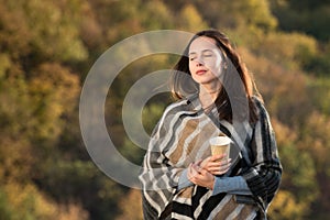 Beautiful girl on nature background of dreams. Travel in the fall. Coffee in hand