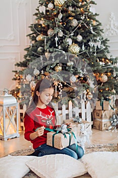 Beautiful girl near a Christmas tree with gifts