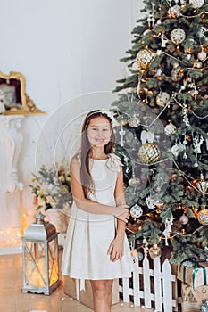 Beautiful girl near a Christmas tree with gifts