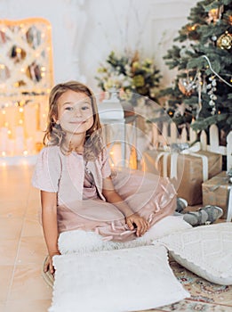 Beautiful girl near a Christmas tree with gifts