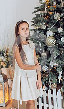 Beautiful girl near a Christmas tree with gifts