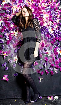 Beautiful girl near the wall with violet flowers