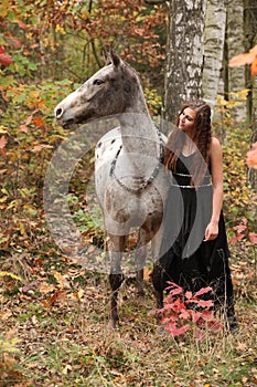 Beautiful girl with nice dress standing next to nice horse