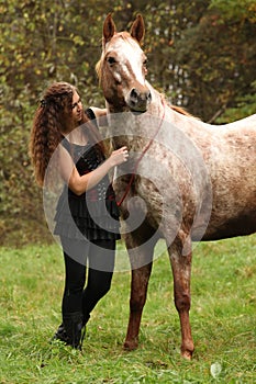 Beautiful girl with nice dress standing next to nice horse