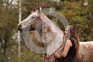 Beautiful girl with nice dress standing next to nice horse