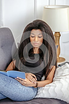 A beautiful girl with a notebook sits on the sofa and makes notes in a notebook