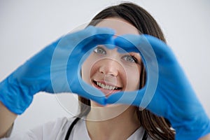 beautiful young girl nurse showing heart in blue gloves doctor surgery helping people care treatment hippocratic oath photo