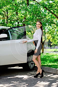 Beautiful girl opens the door of her car and going to sit down in the driver seat